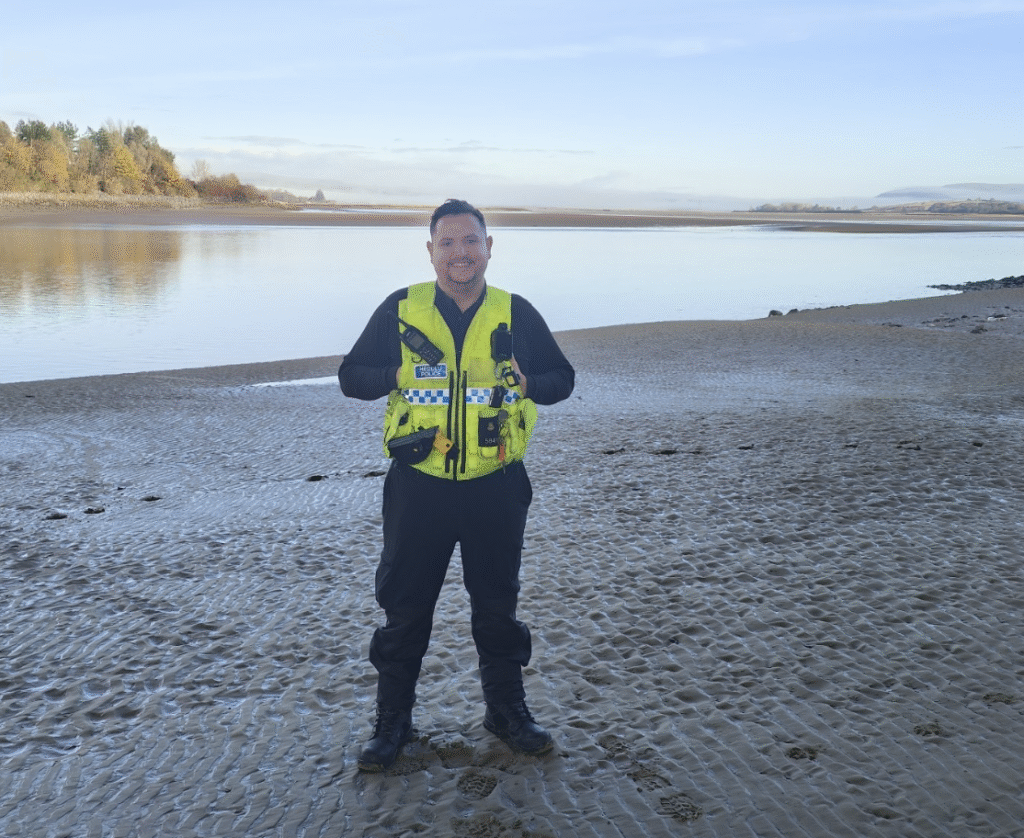 New rep Matthew Stanley stands next to a lake with his police uniform on
