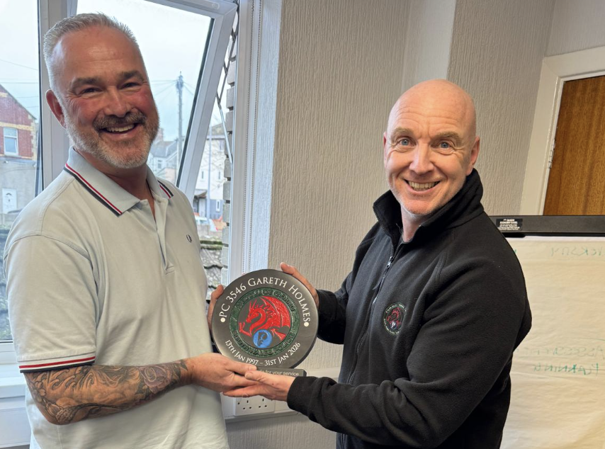Branch secretary Mike George (right) in a dark top presents an award for long service to PC Gareth Holmes (left)
