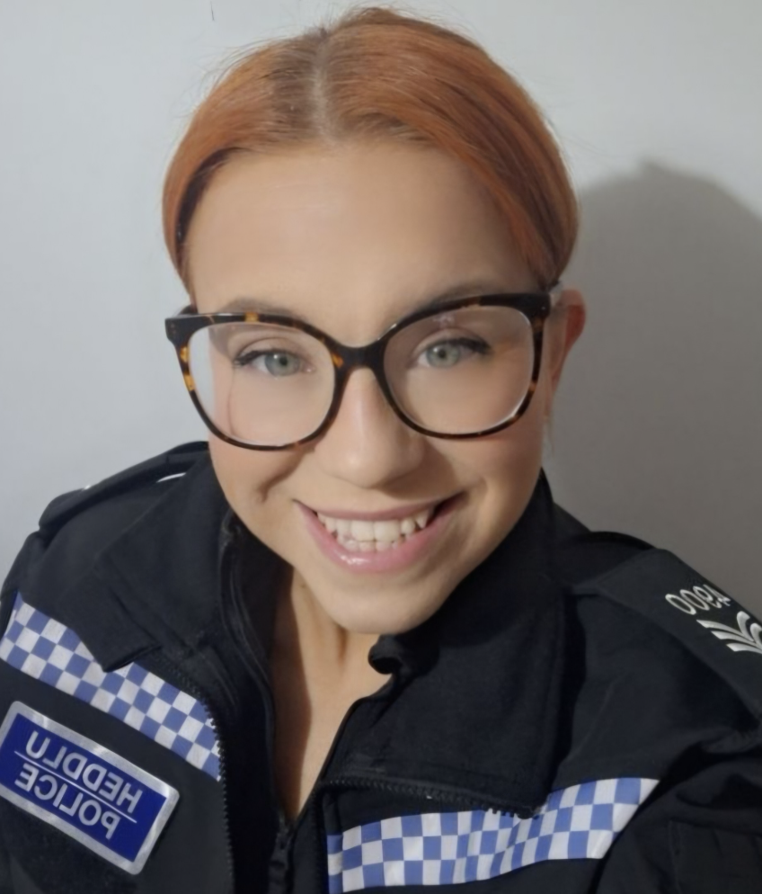 Sergeant Carli Shellard wears big-rimmed glasses and smiles while wearing police uniform