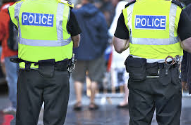 The back of two police officers in uniform with yellow high-vis vests