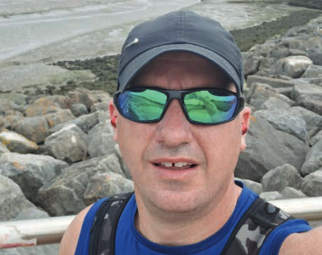 Richard ‘Reggie’ George wears a grey cap and a blue vest wearing reflective sunglasses