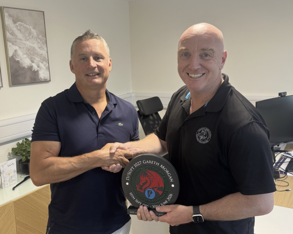 DS Gareth Morgan, wearing a blue polo shirt, is presented with a long-service plaque by branch secretary Mike George, who is bald and wearing a black polo shirt.