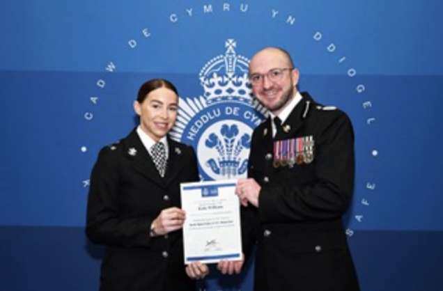 Special Constable Katie Williams with Dr Dale Cartwright, Chief Officer, South Wales Police Special Constabulary, dressed in official policing clothing hold a certificate.