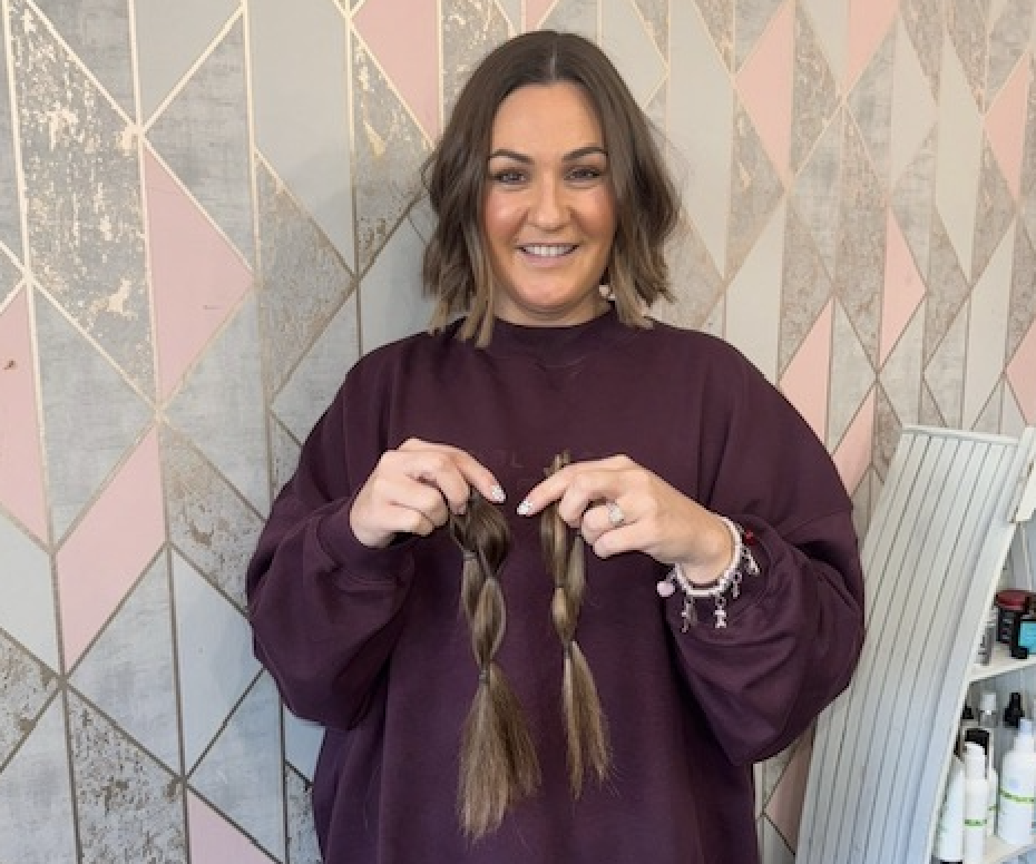 Jo Ferguson smiles wearing a jumper holding two strands of hair