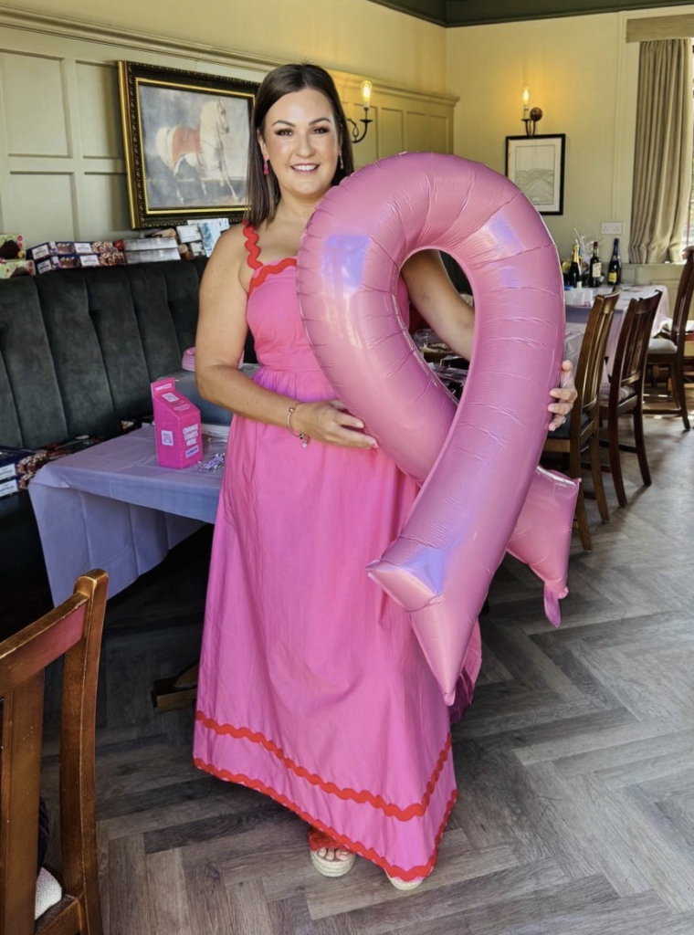 Jo Ferguson is dressed in pink with a big pink balloon